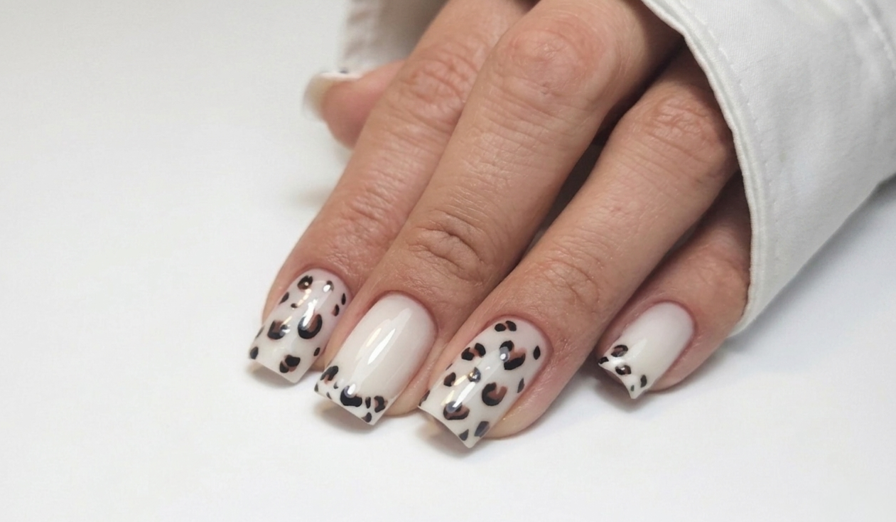 Vierkante nagels, om en om wit en met luipaardprint, hand op een witte mouw